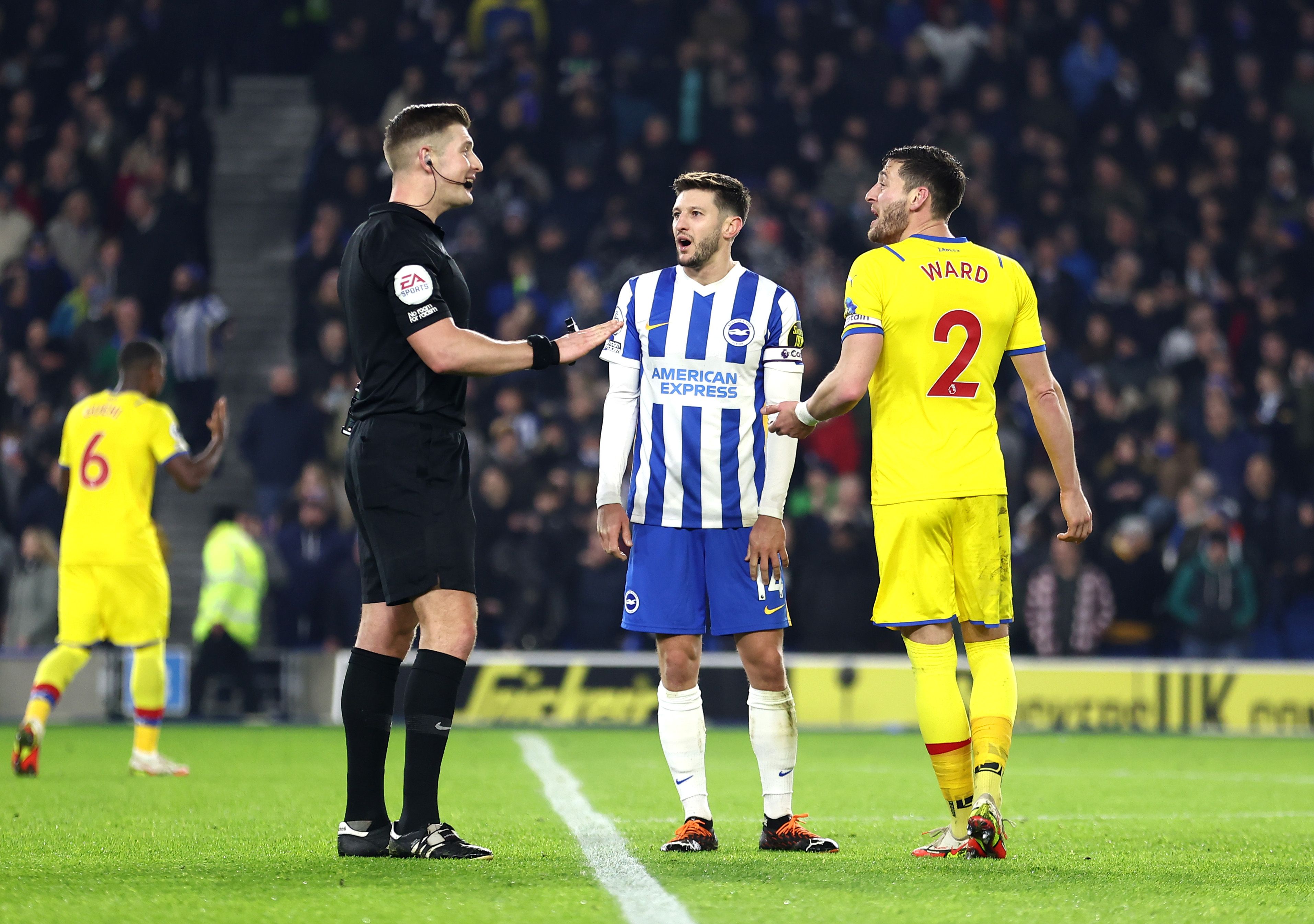 Adam Lallana of Brighton &amp; Hove Albion and Joel Ward of Crystal Palace speak to referee Robin Jones after a VAR incident during the Premier League match between Brighton &amp; Hove Albion and Crystal Palace at American Express Community Stadium on January 14, 2022 in Brighton, England.