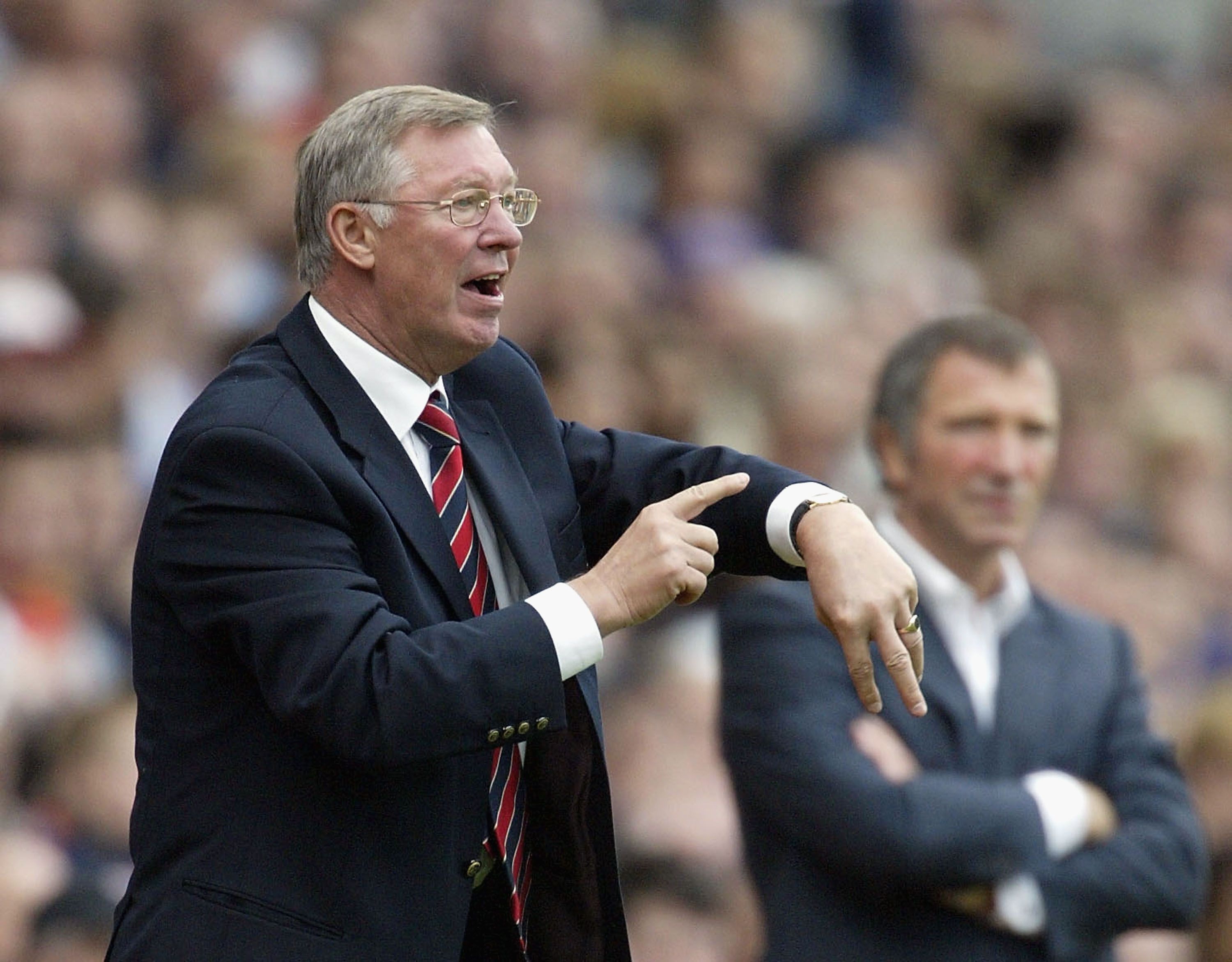 Sir Alex Ferguson points to his watch to signal the end of the game to officials