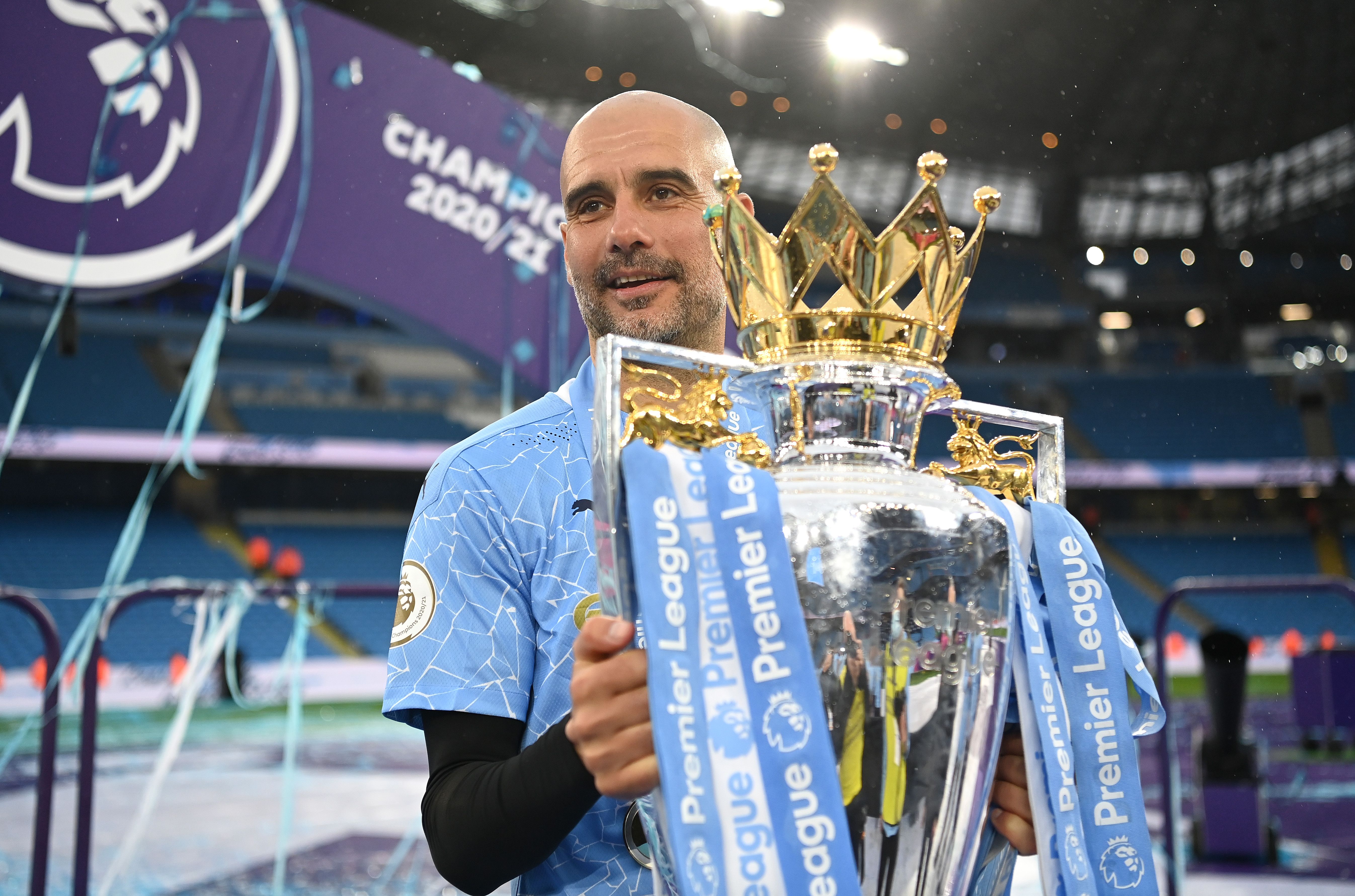 Pep Guardiola holding the Premier League trophy at Manchester City