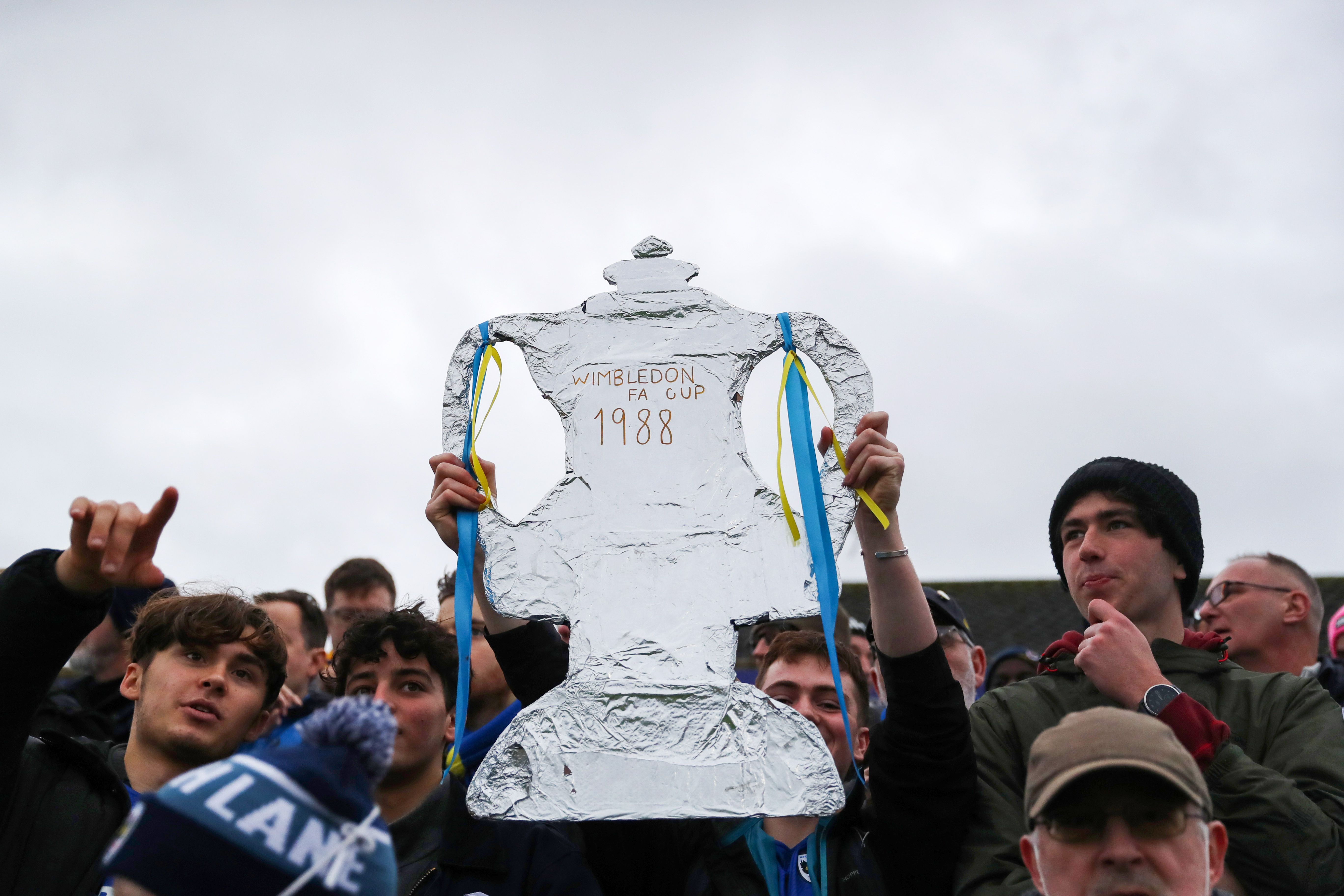 A fan of AFC Wimbledon holds up a Tin foil FA Cup Trophy during the Emirates FA Cup Third Round match between Boreham Wood and AFC Wimbledon at Meadow Park on January 08, 2022 in Borehamwood, England.
