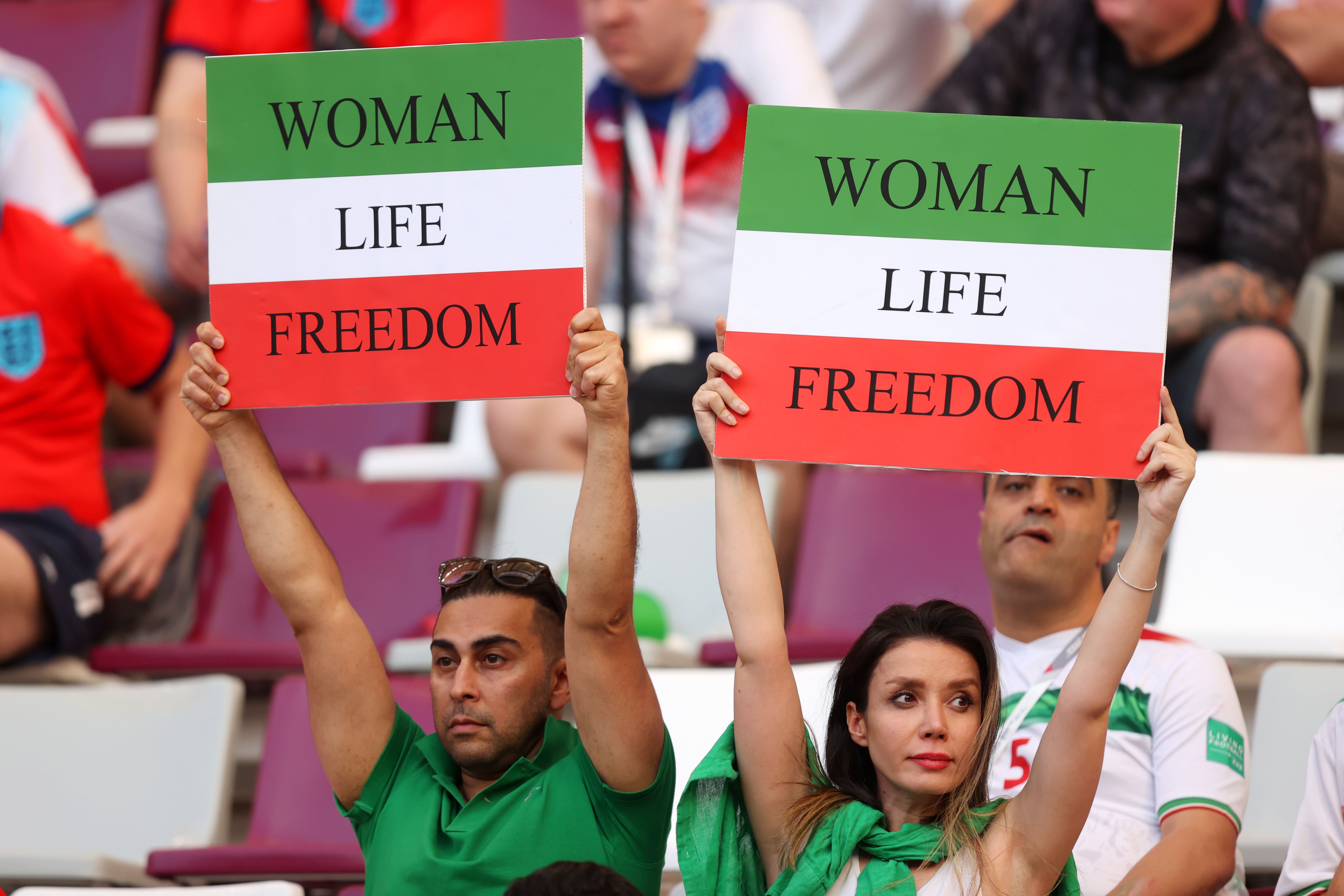 Iranian fans hold up signs advocating for women's rights at the 2022 World Cup