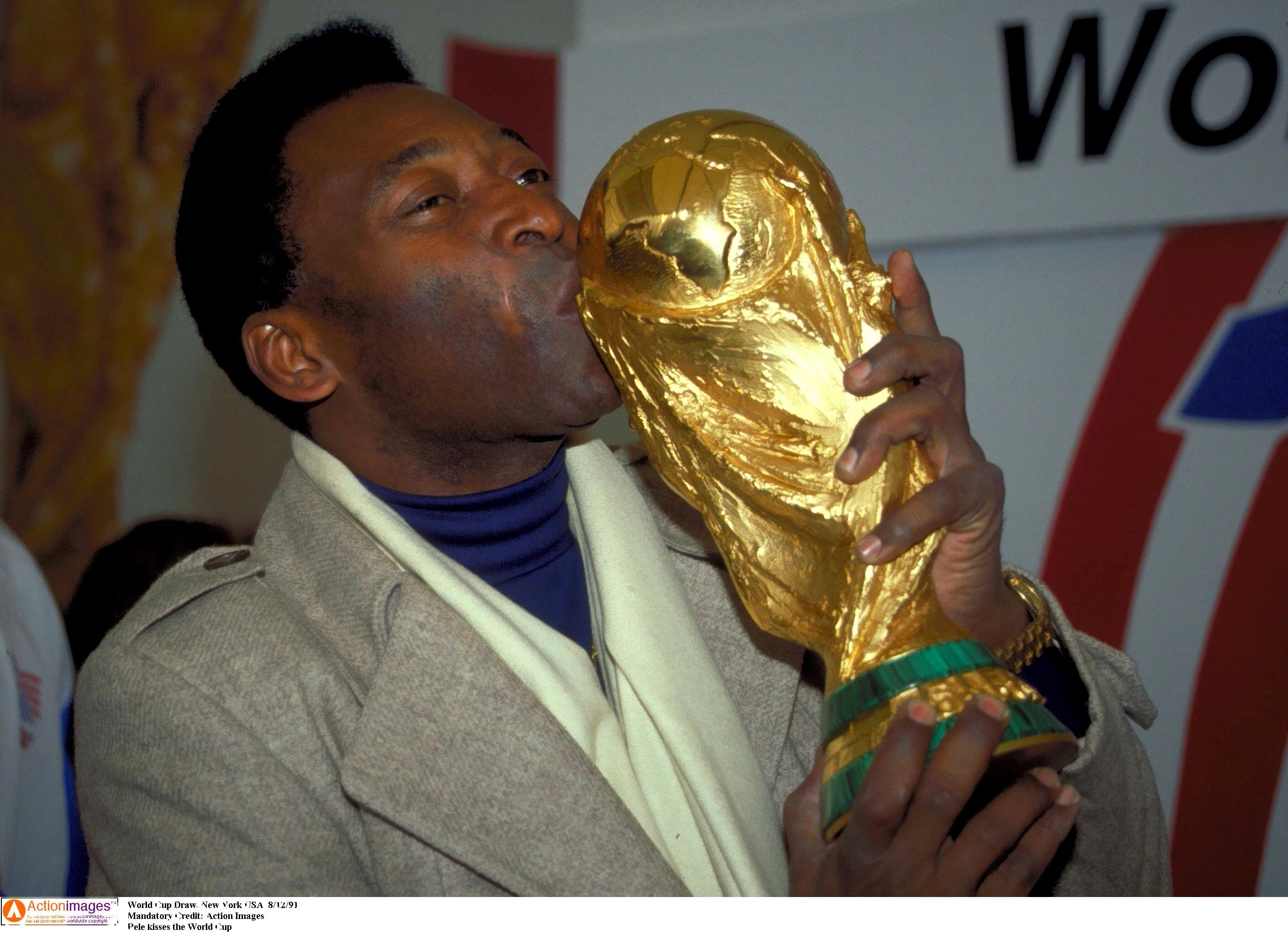 Pele kisses the World Cup trophy.