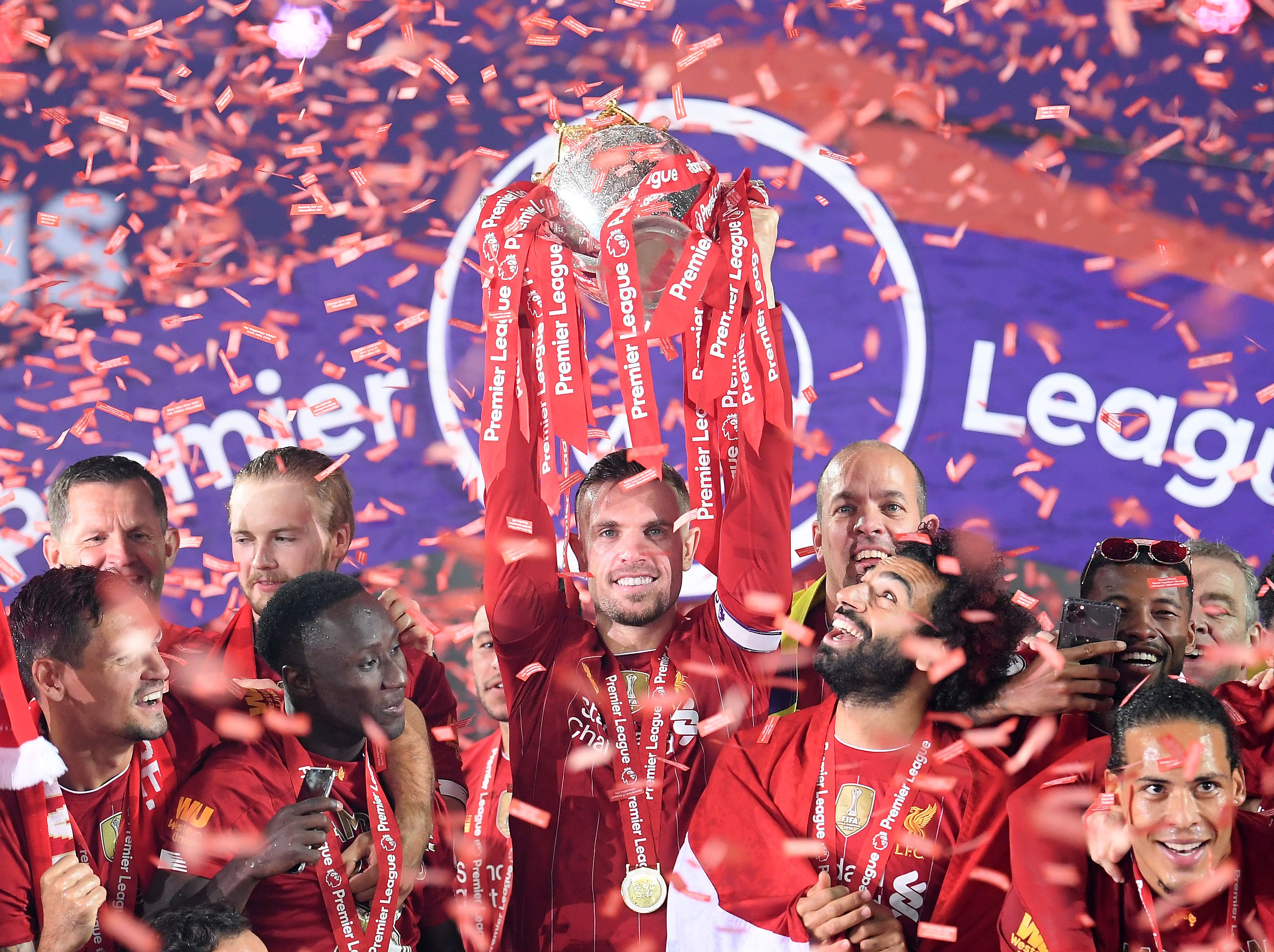 Jordan Henderson of Liverpool holds the Premier League Trophy aloft.