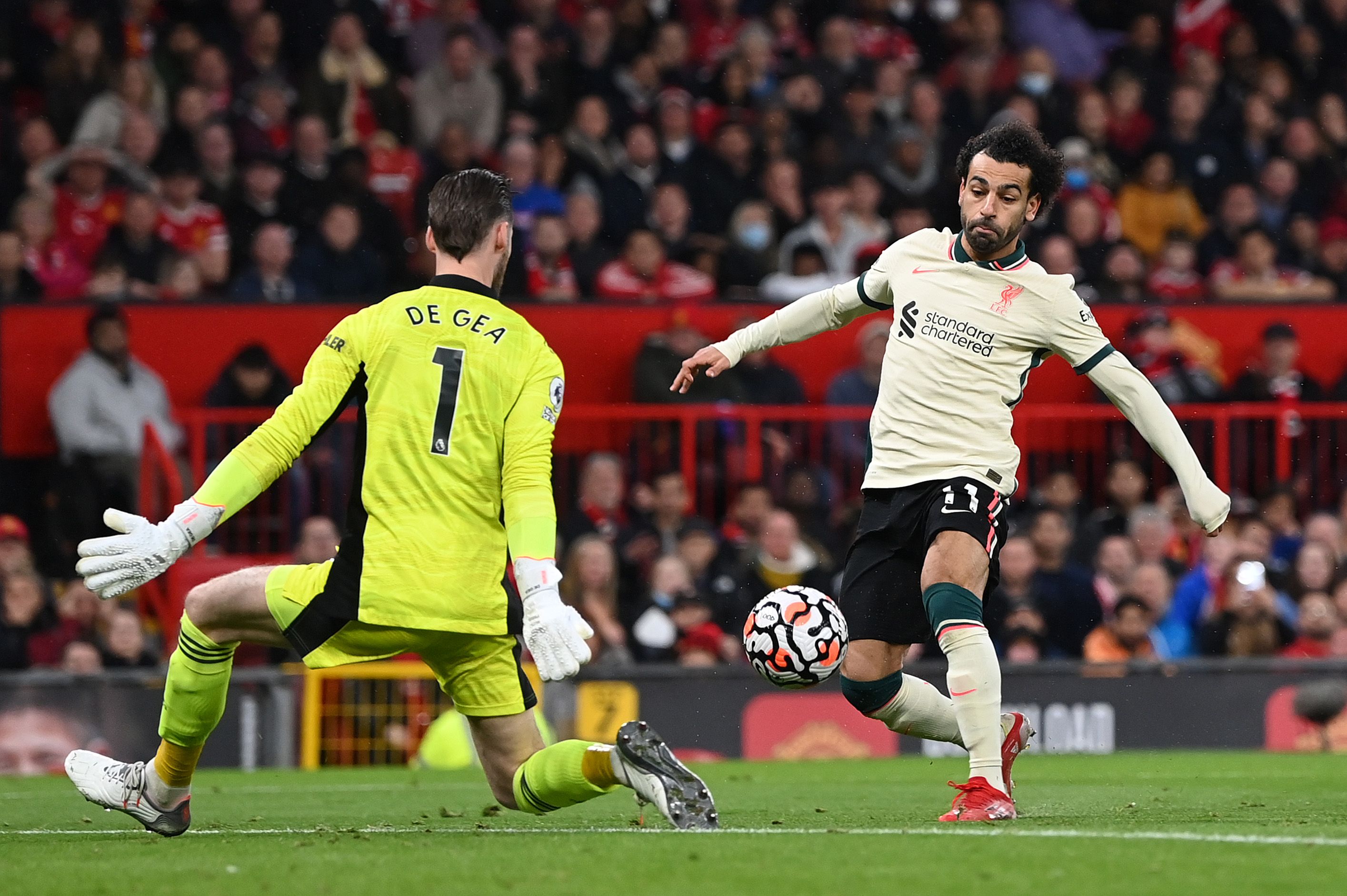 MANCHESTER, ENGLAND - OCTOBER 24: Mohamed Salah of Liverpool shoots past Manchester United goalkeeper David De Gea to score his hat trick during the Premier League match between Manchester United and Liverpool at Old Trafford on October 24, 2021 in Manchester, England. (Photo by Shaun Botterill/Getty Images)
