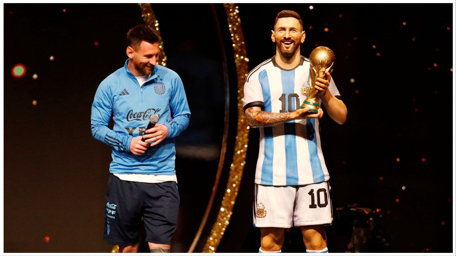 Lionel Messi standing next to his life-size statue