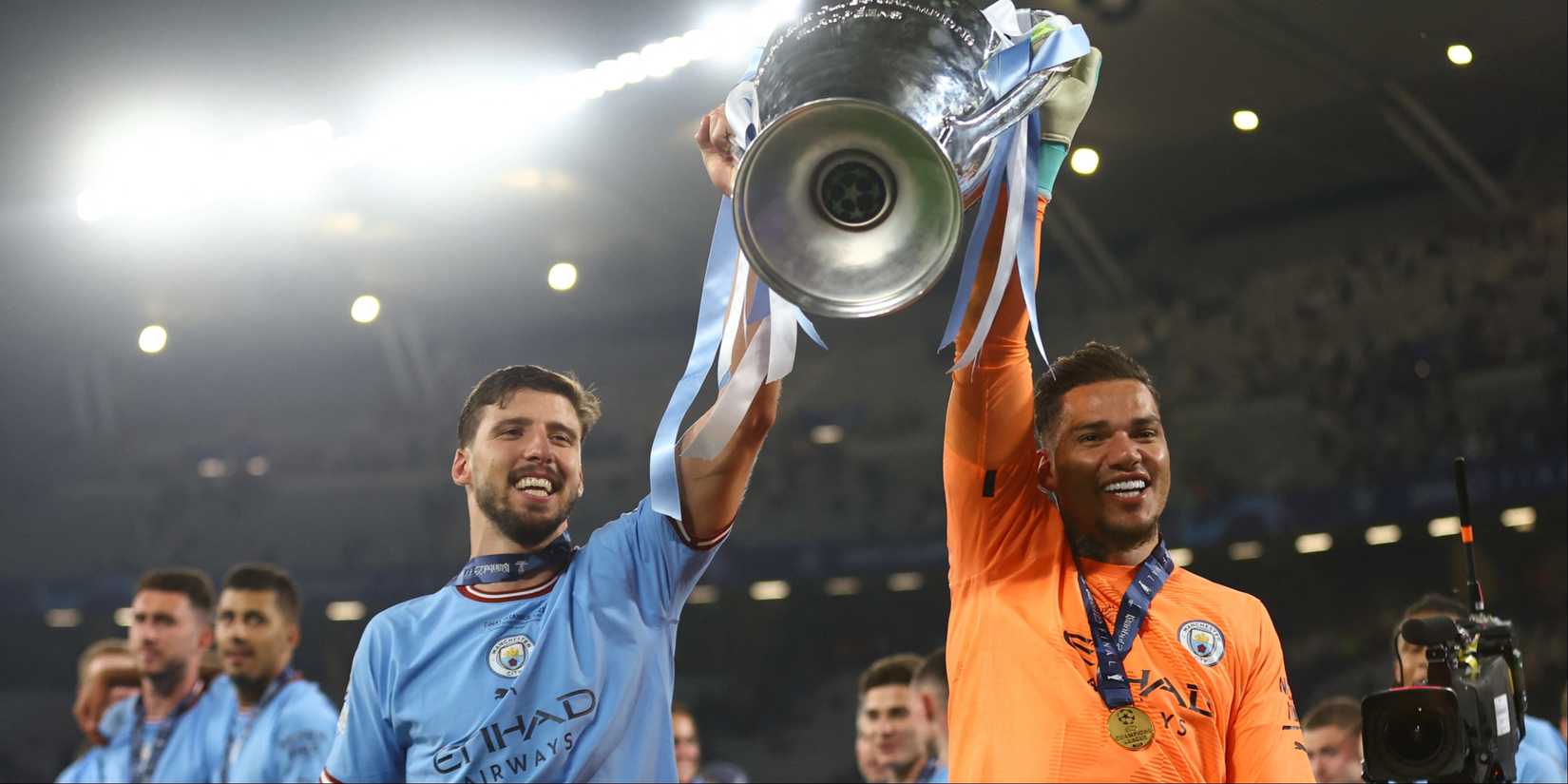 Manchester City's Ruben Dias and Ederson celebrate with the trophy after winning the Champions League.