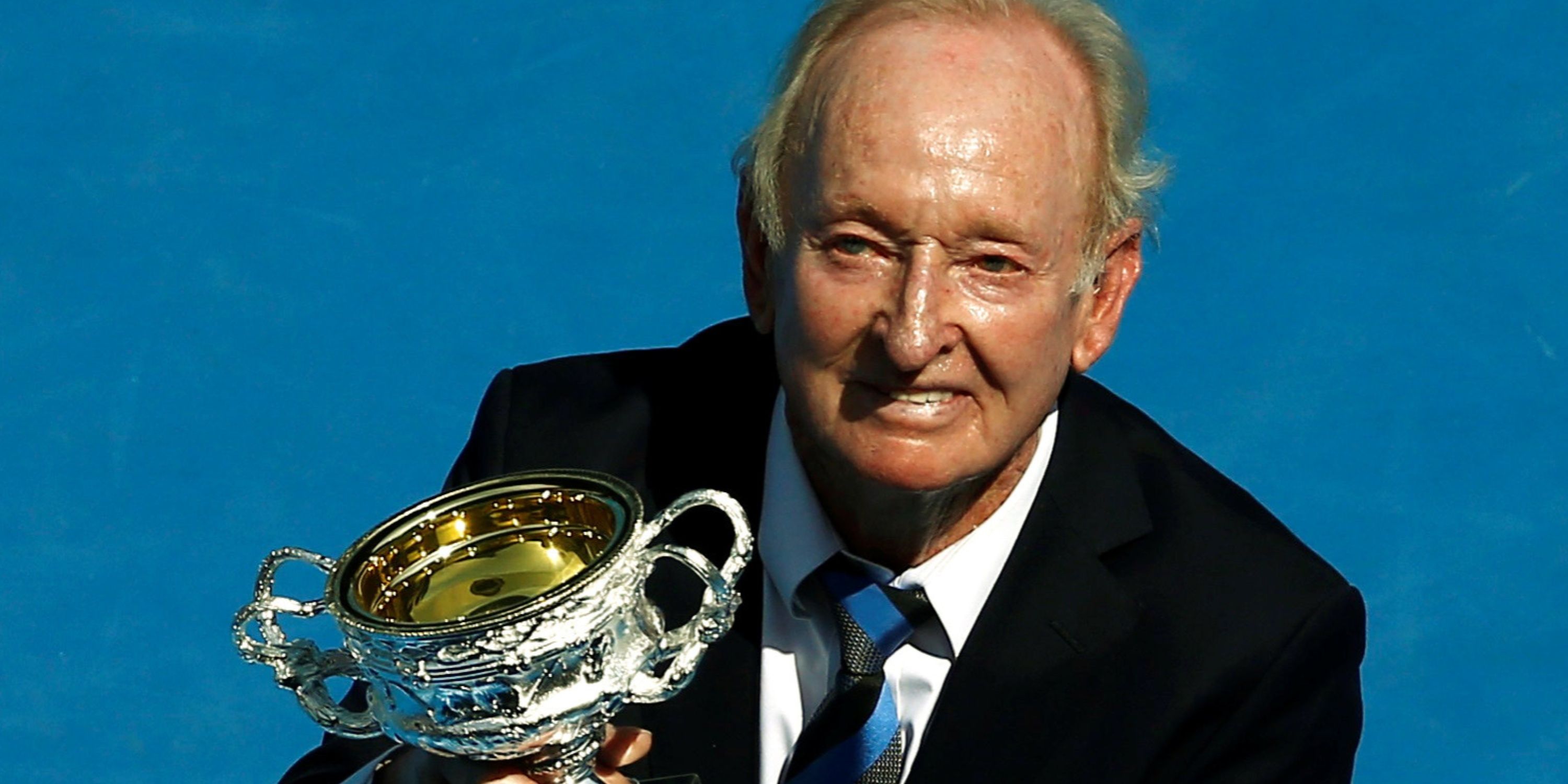 Former Australian tennis player Rod Laver holds a trophy presented to him.