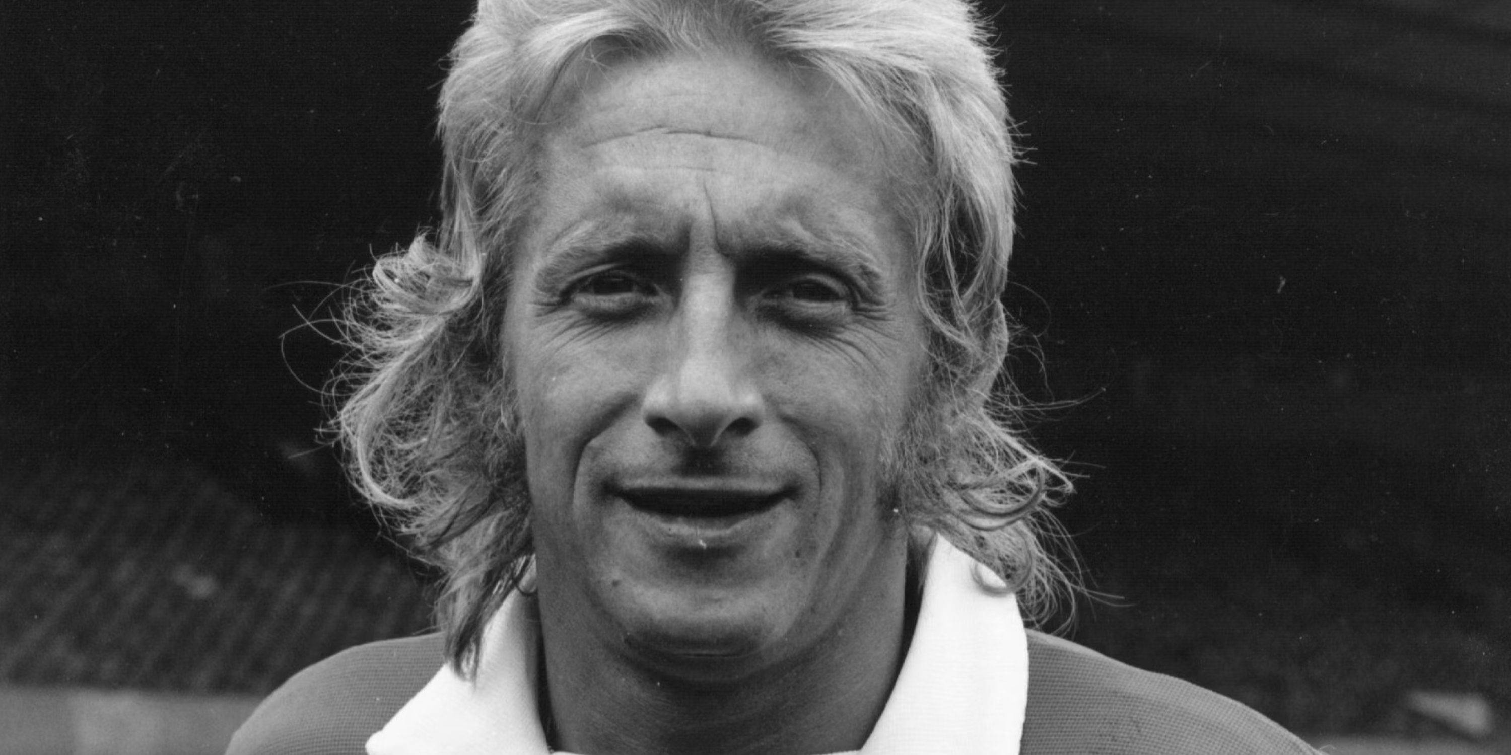 A black and white image of Denis Law looking on while representing Manchester United