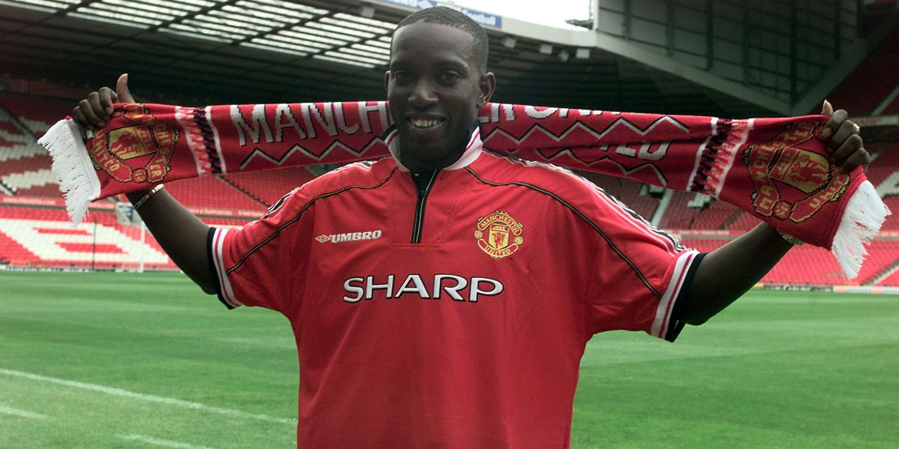 Dwight Yorke holds aloft a Manchester United scarf after signing for the club.