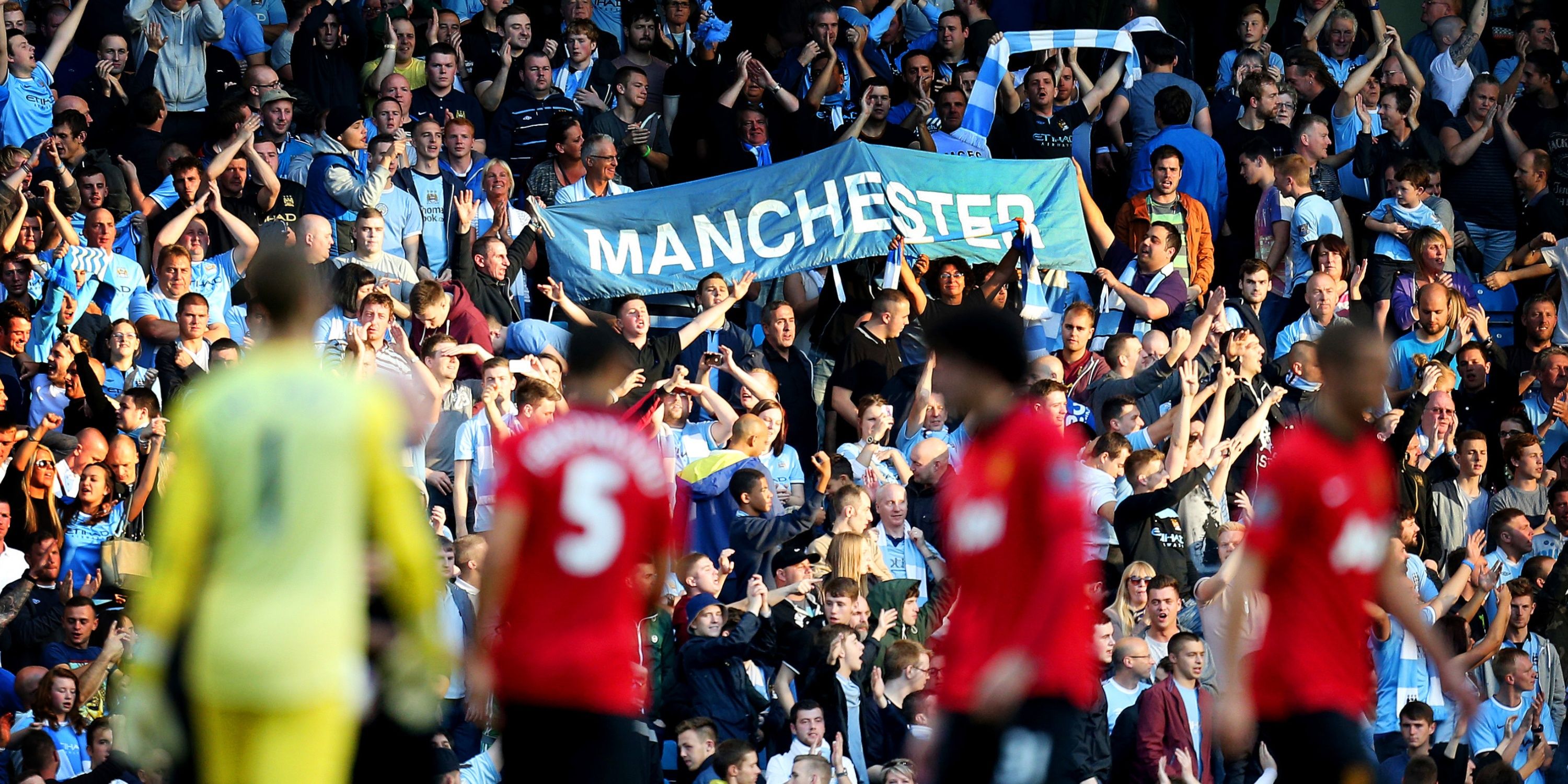 Manchester City fans hoist a sky blue 'Manchester' ban after watching their side beat Manchester United 4-1.