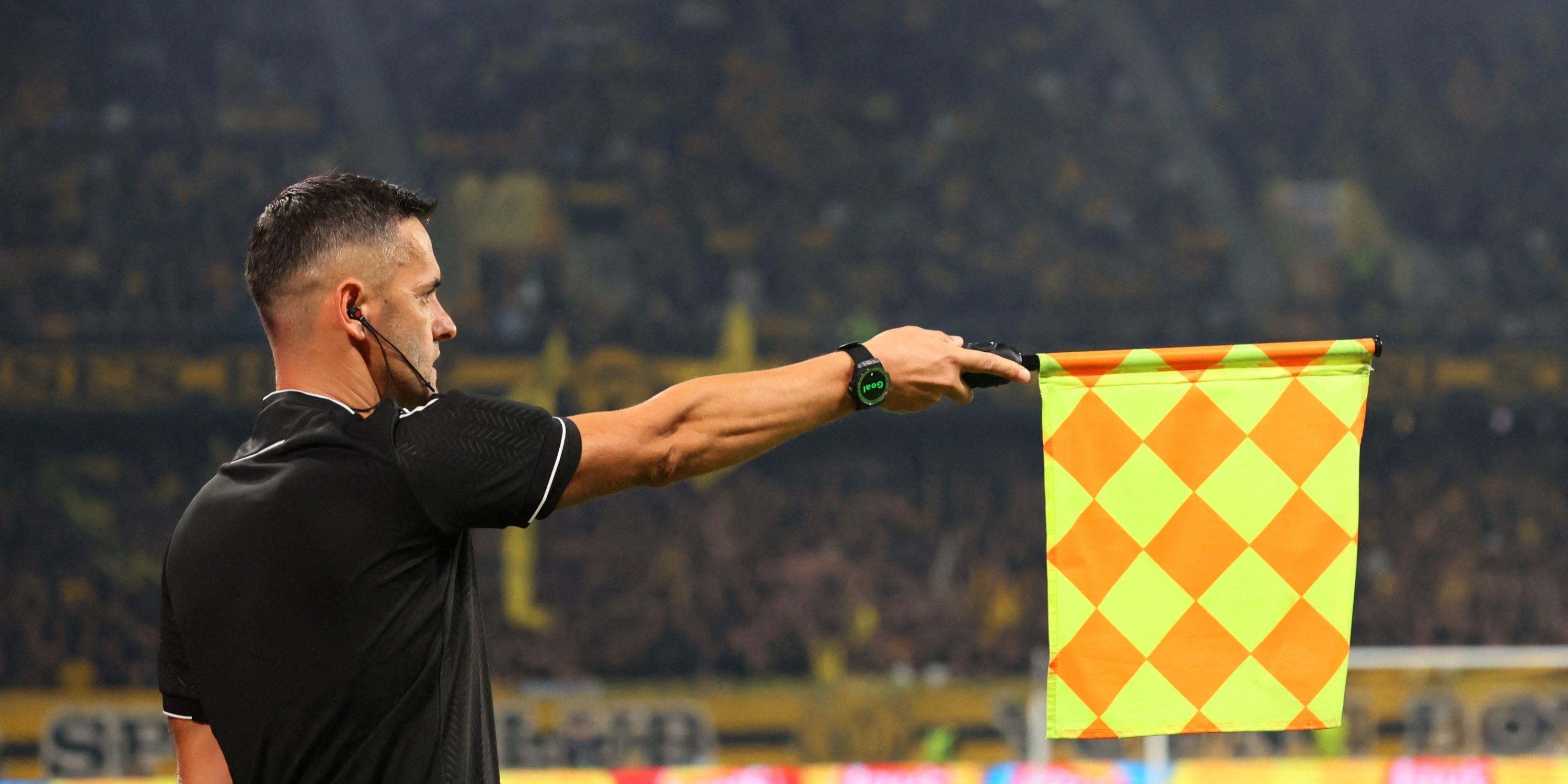 The linesman holding out his flag in a game of soccer.