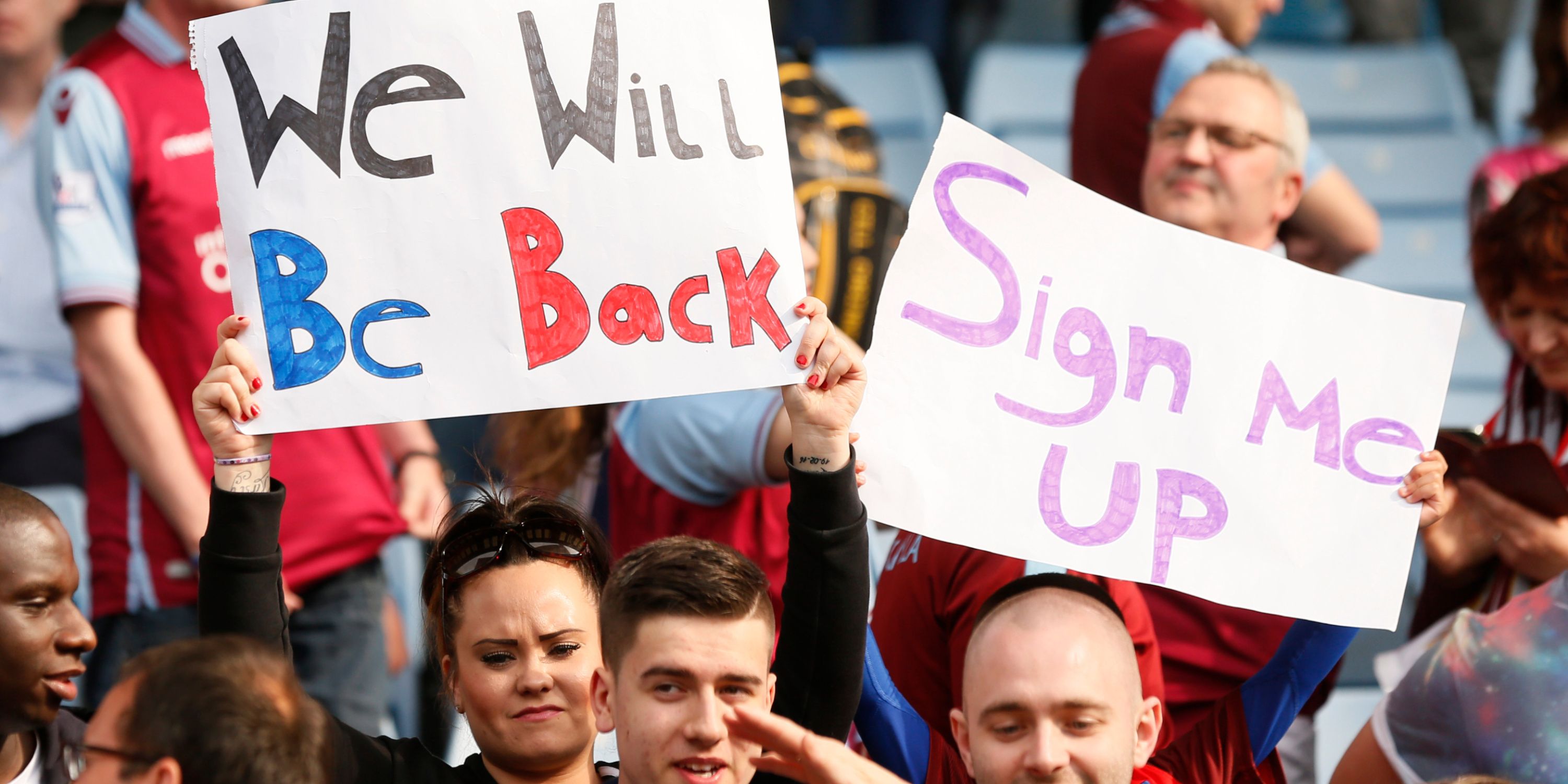 Aston Villa fans hold up signs in response to Premier League relegation