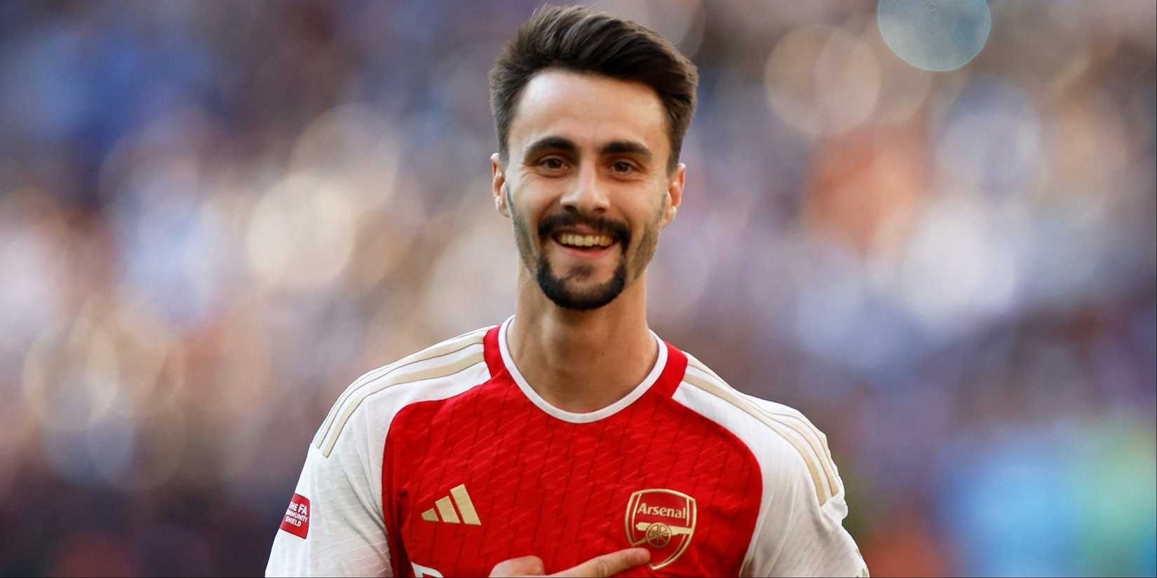 A smiling Fabio Vieira points to the Arsenal badge after victory in the Community Shield. 