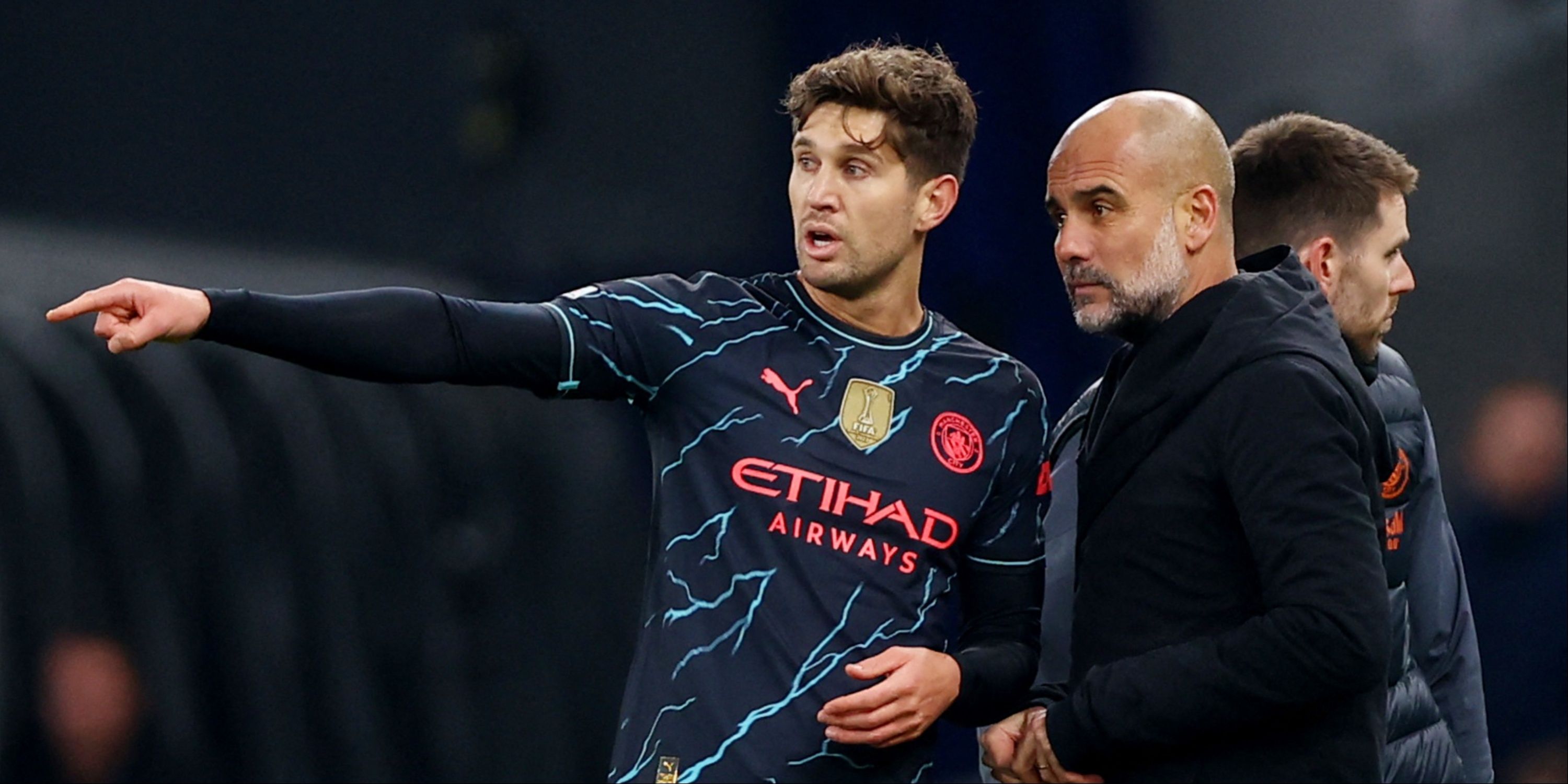 Manchester City manager Pep Guardiola and player John Stones discuss tactics on the touchline.