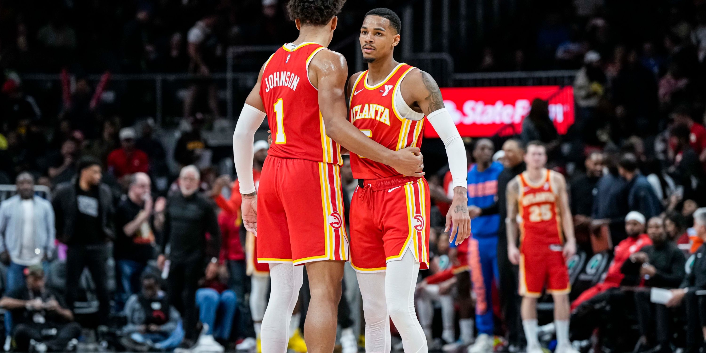 Hawks starters Dejounte Murray and Jalen Johnson hug at center court