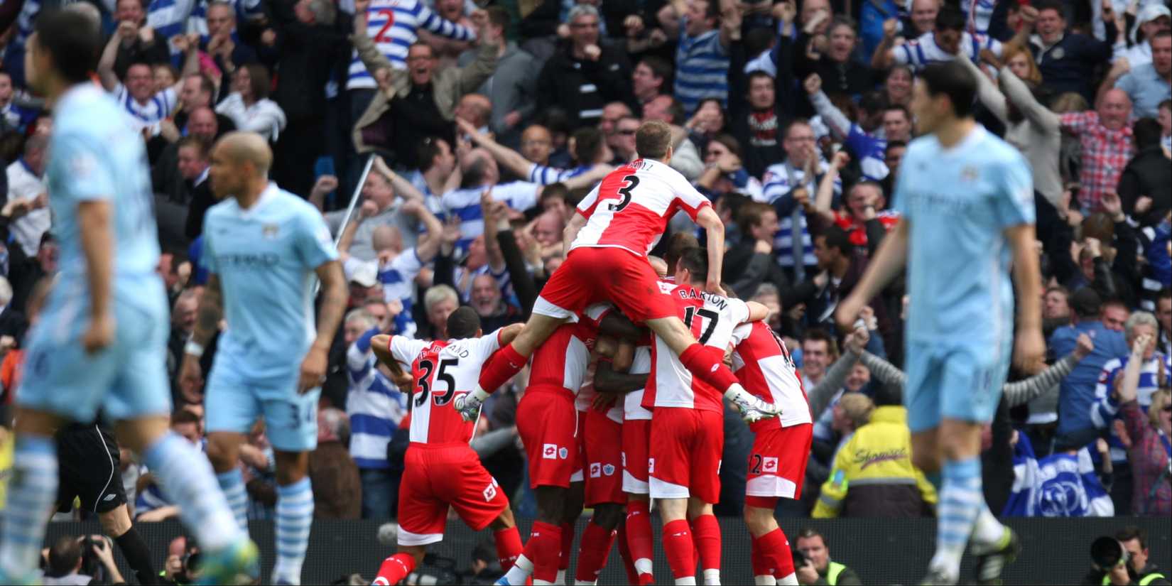 QPR players celebrate as Manchester City players trudge back to the halfway line.