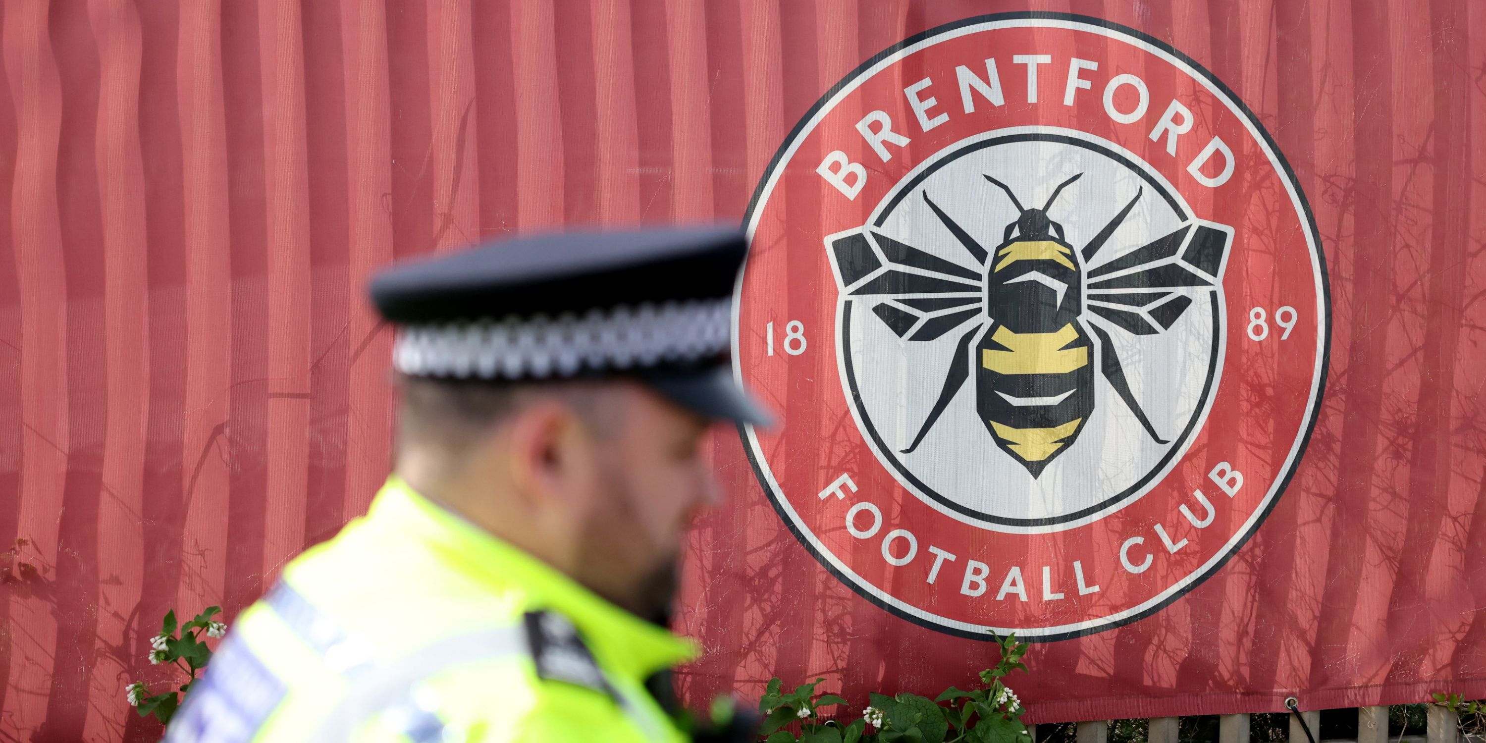 A police officer walking in front of Brentford's badge