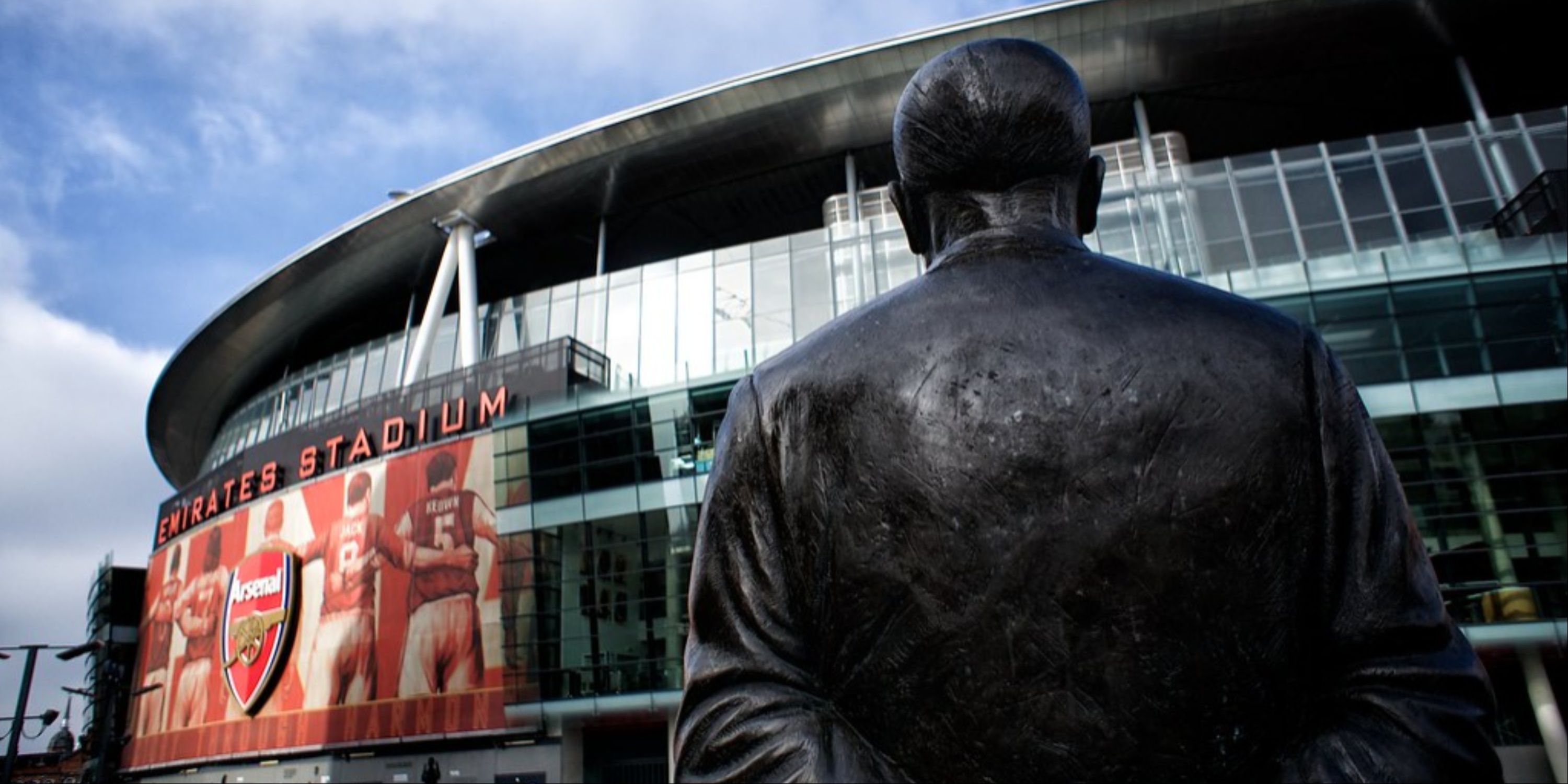 A statue of manager Herbert Chapman looking at Arsenal's Emirates Stadium.