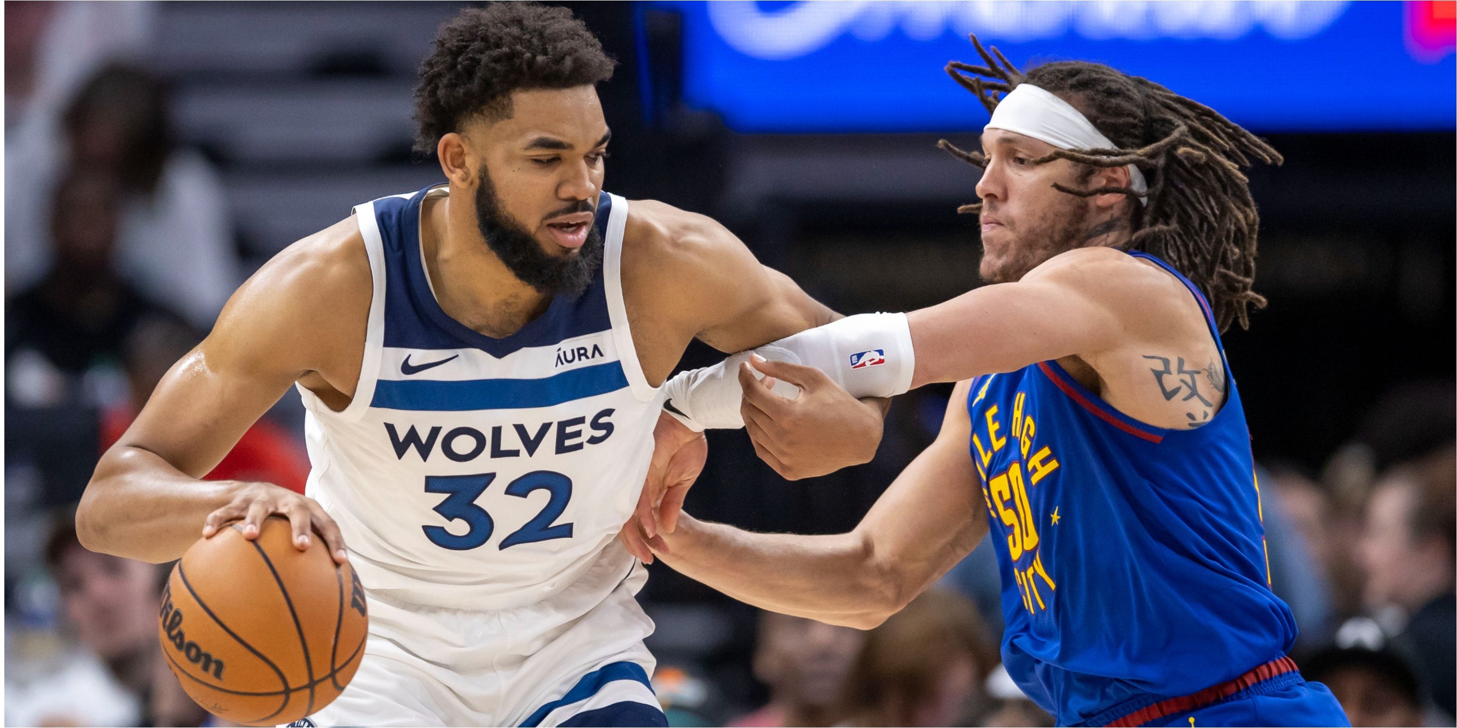 Minnesota Timberwolves forward Karl-Anthony Towns dribbles the ball against Aaron Gordon of the Denver Nuggets during the 2024 NBA Playoffs.