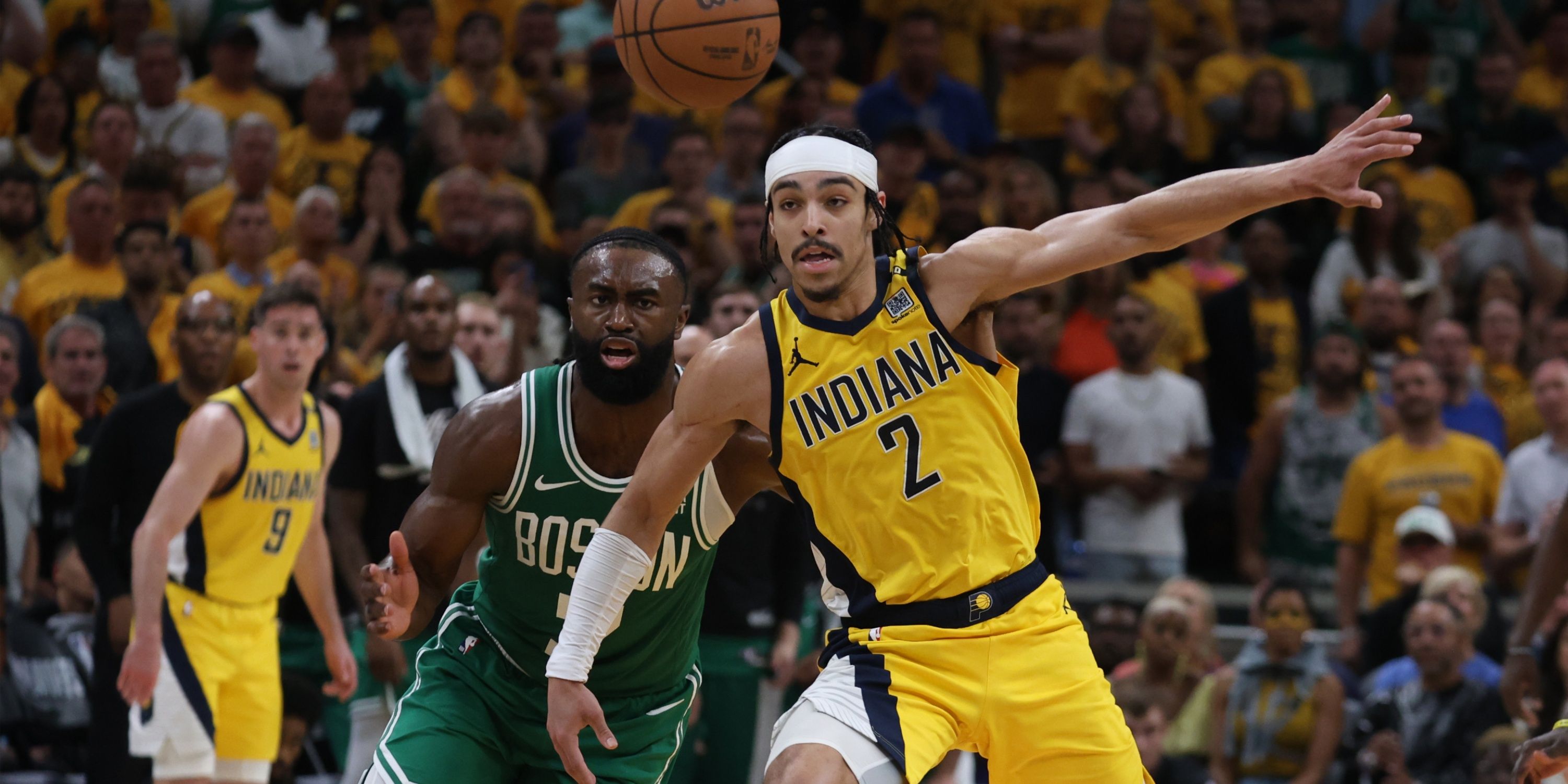 Indiana Pacers' guard Andrew Nembhard and Boston Celtics guard/forward Jaylen Brown fighting for a loose ball during Game 3 of the 2024 Eastern Conference Finals.