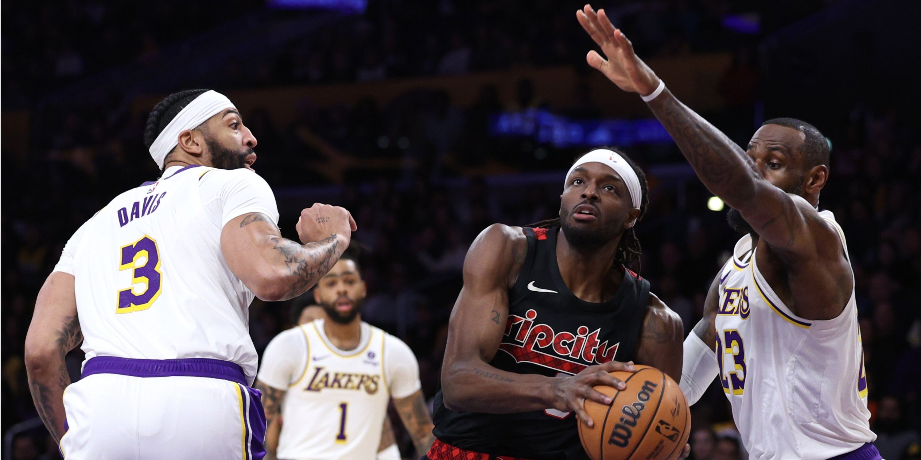 Jerami Grant of the Portland Trail Blazers drives between LeBron James and Anthony Davis of the Los Angeles Lakers