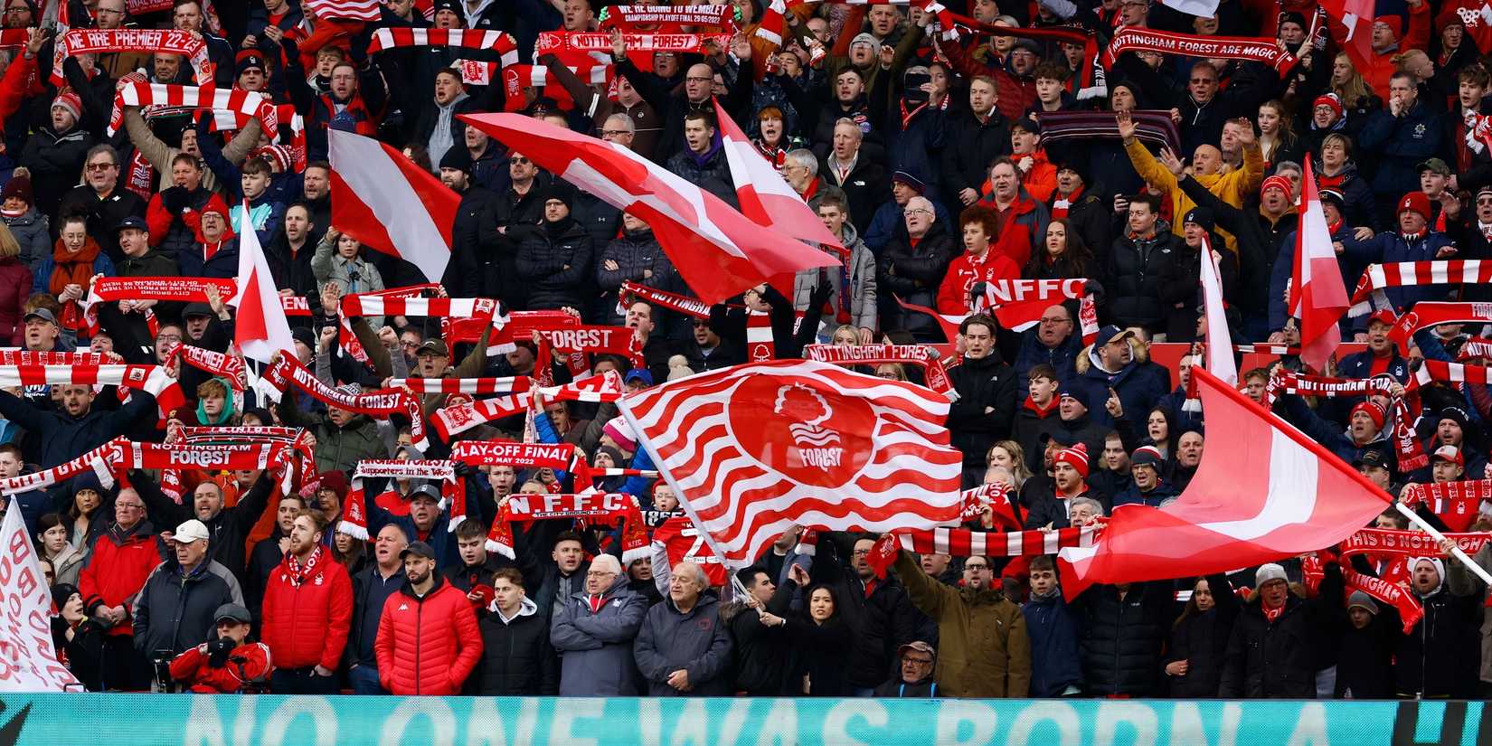 Nottingham Forest fans wave flags and hold their scarves up in support of their team.