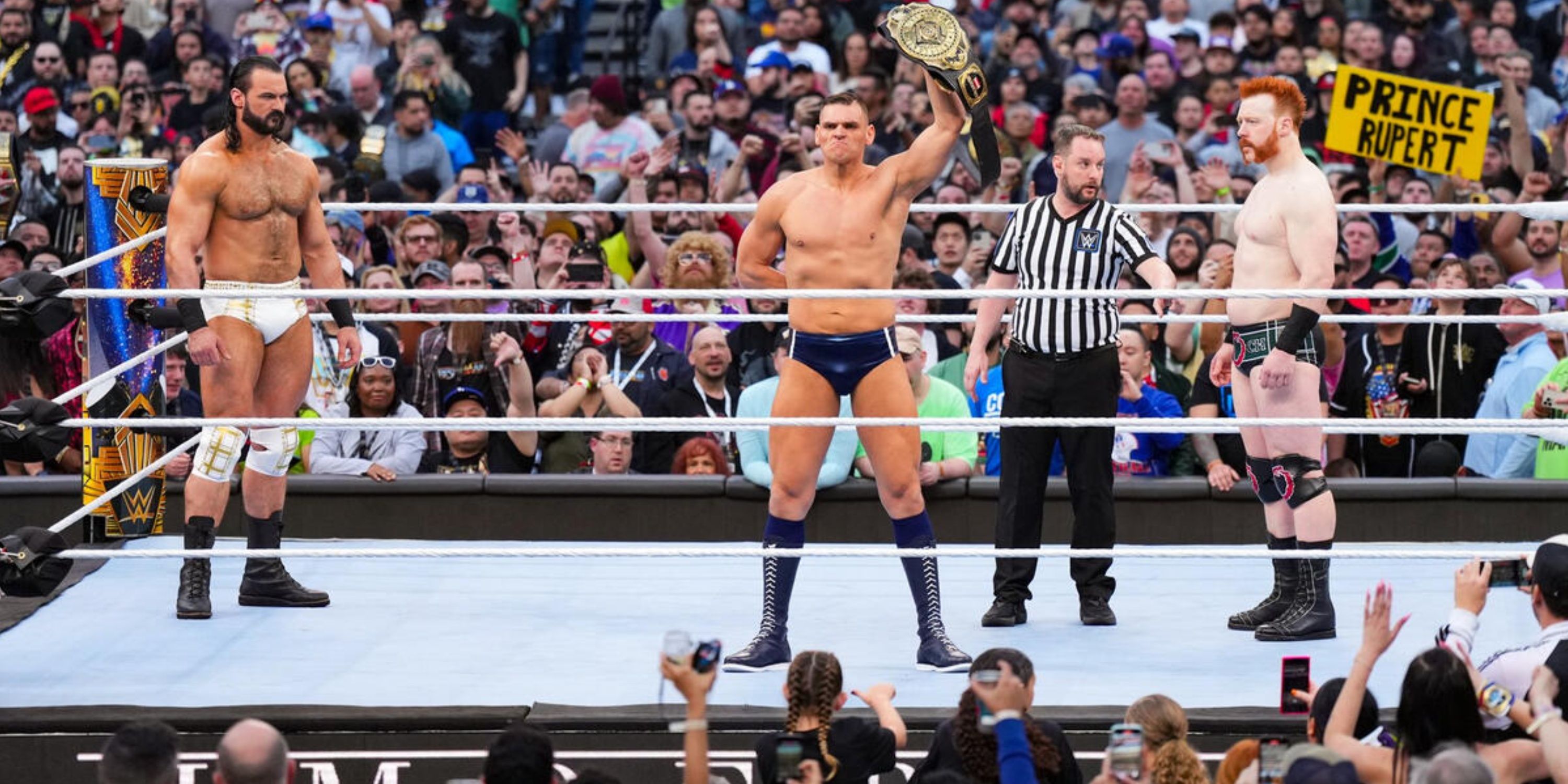 GUNTHER poses with the WWE Intercontinental Championship in the ring with Sheamus and Drew McIntyre at WrestleMania 39