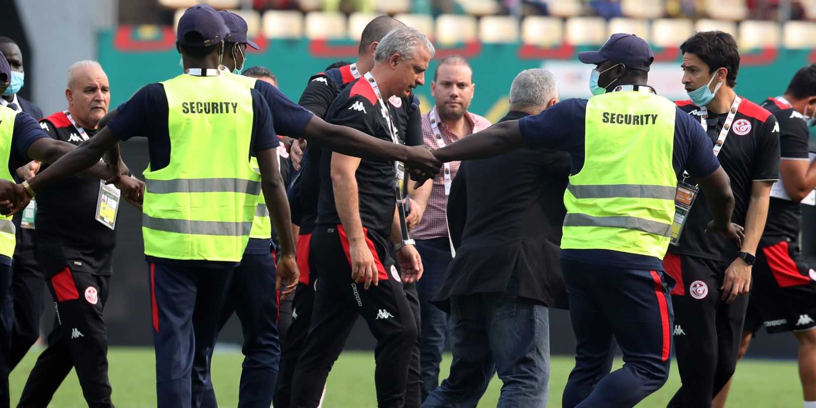 Security protect Tunisia coach Mondher Kebaier as he walks off the pitch after the match