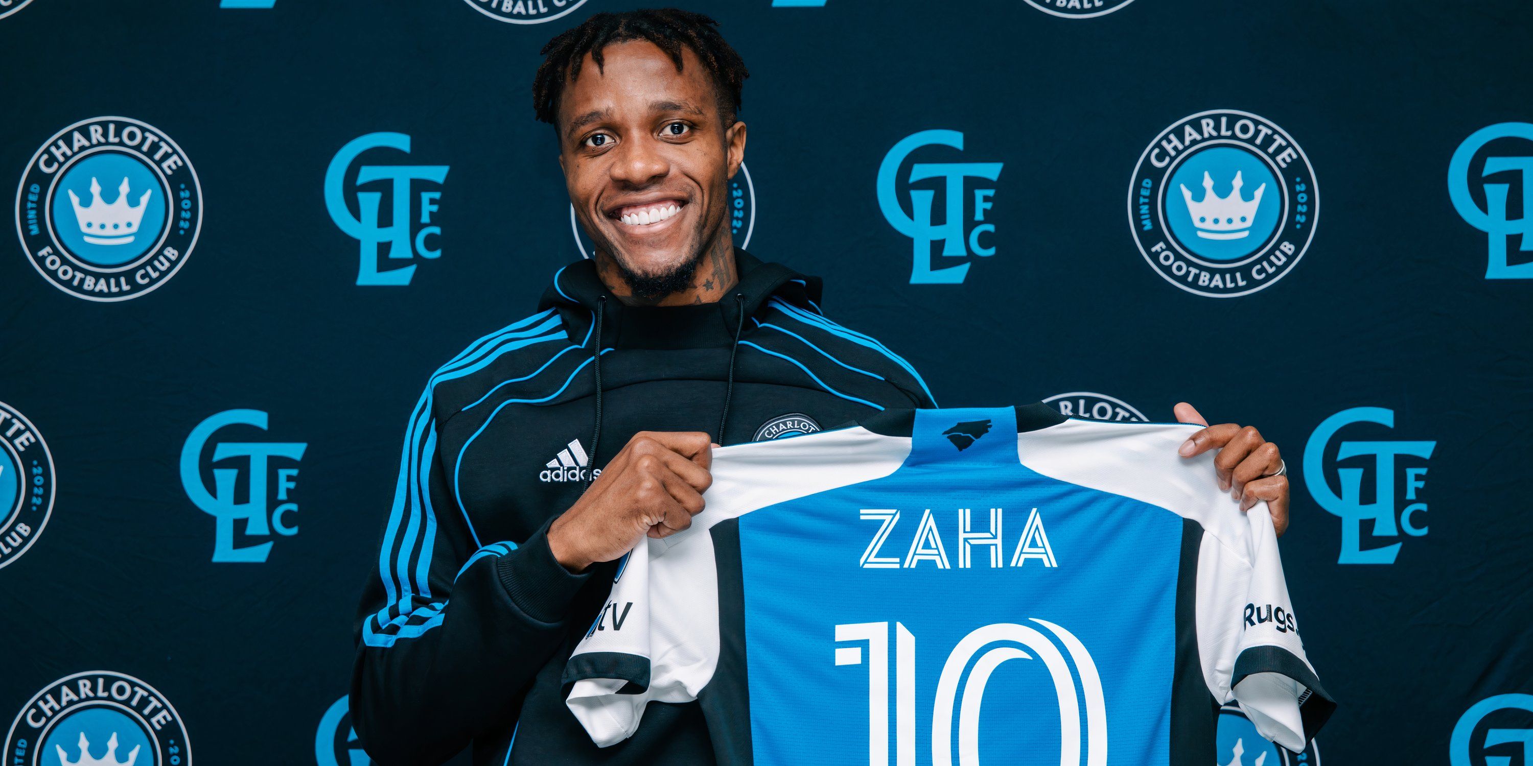 Wilfried Zaha holding his Charlotte FC shirt after joining