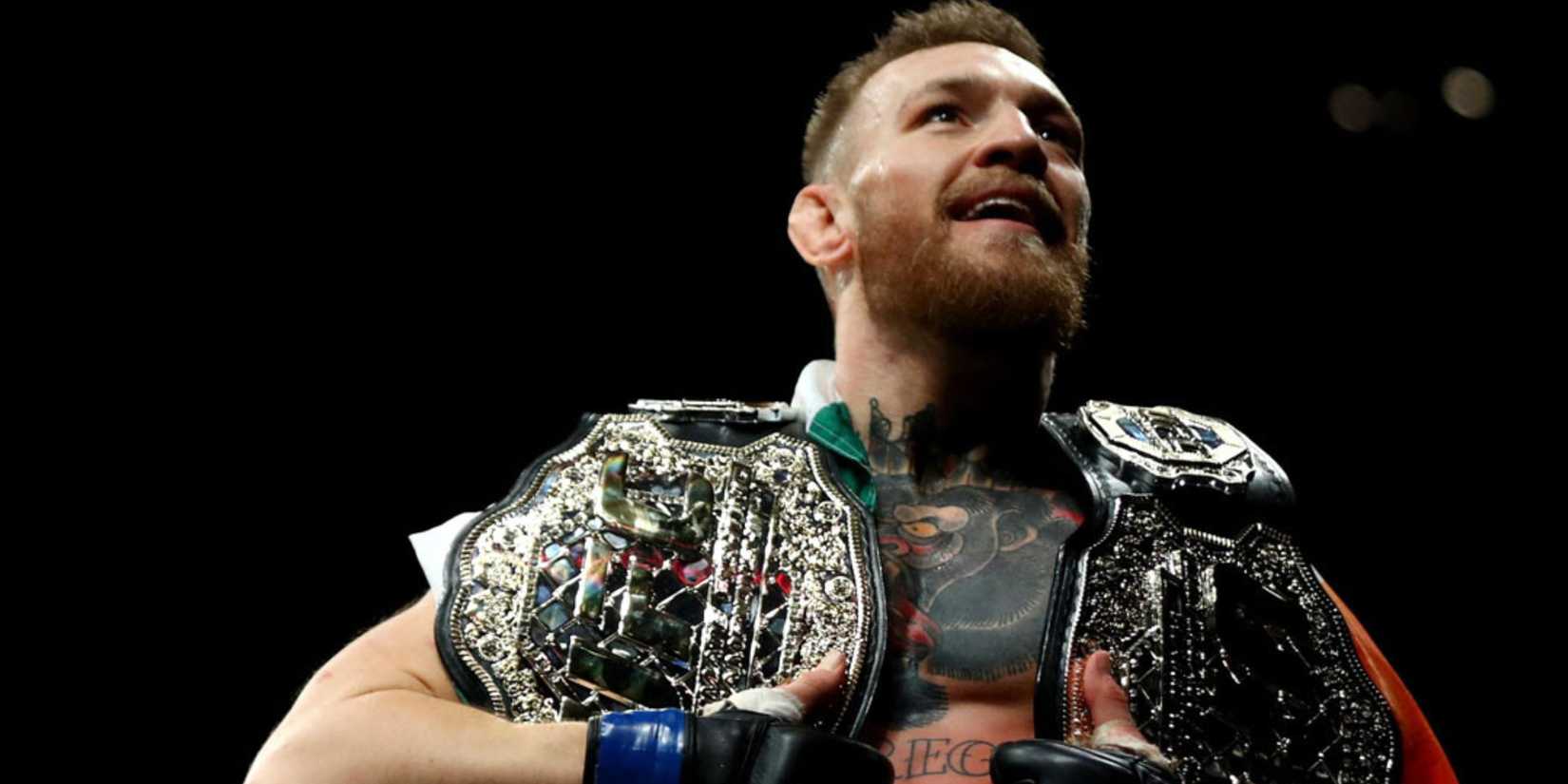 Conor McGregor holding two UFC belts-1