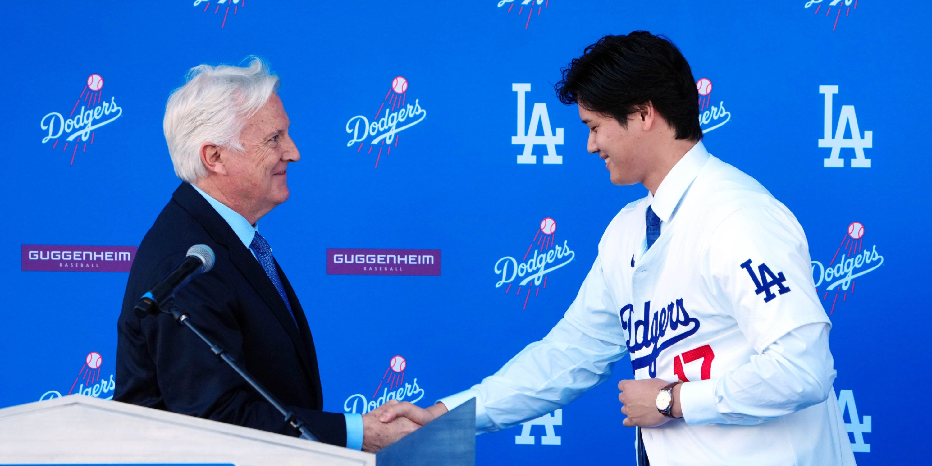 LA Dodgers lead owner Mark Walter shakes hands with Shohei Ohtani.
