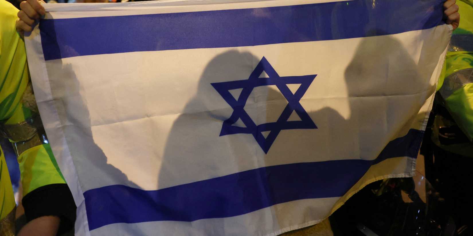 Police officer escort a protester carrying the flag of Israel