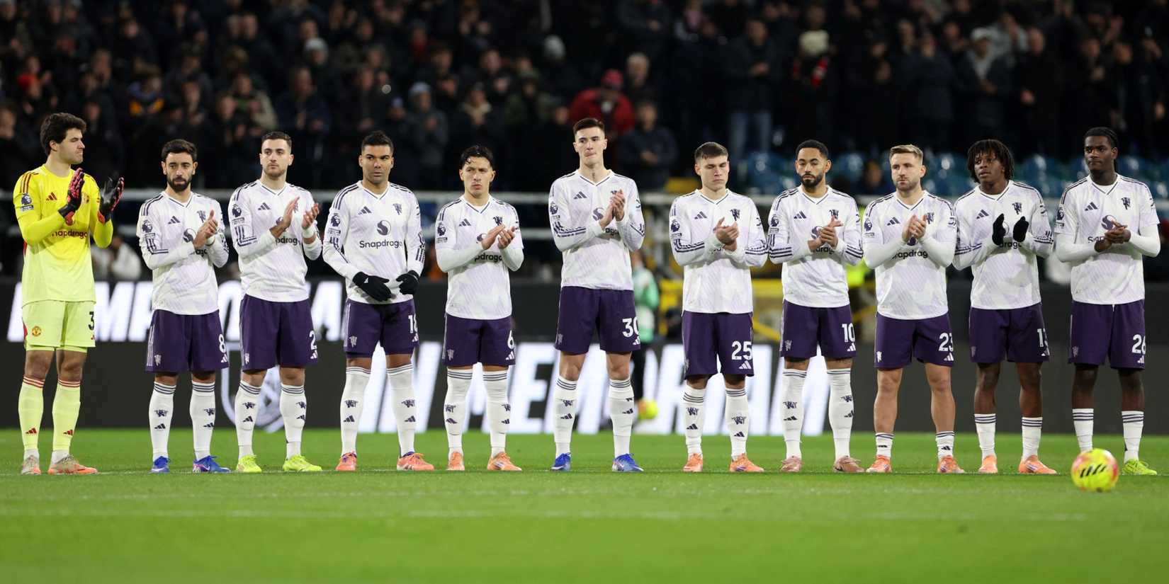 Manchester United players line up during a minutes applause before the match