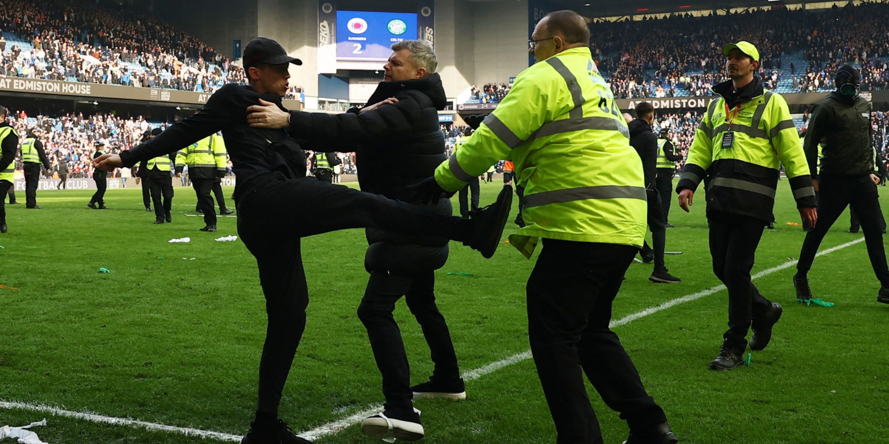 Rangers fan clashes with a steward on the pitch after the Celtic match