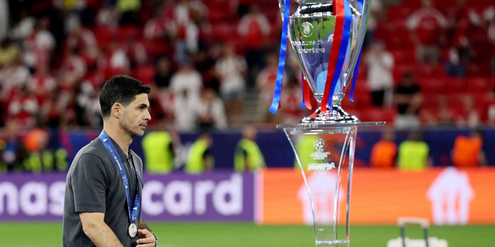 Mikel Arteta walks past Champions League trophy