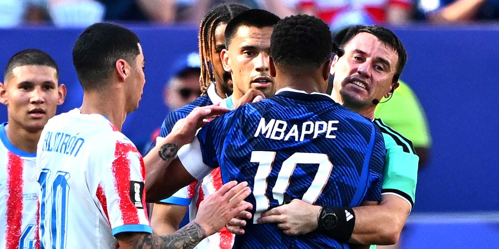 Referee Ilgiz Tantashev reacts with France's Kylian Mbappe after players clash
