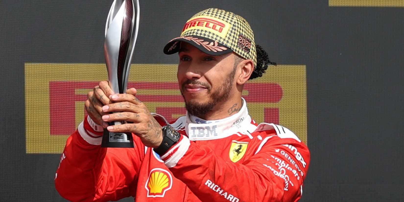 Ferrari's Lewis Hamilton celebrates with his trophy on the podium after finishing third in the British Grand Prix
