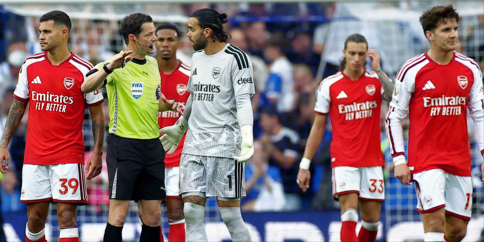 Arsenal players at the Amex stadium, with David Raya in conversation with referee.