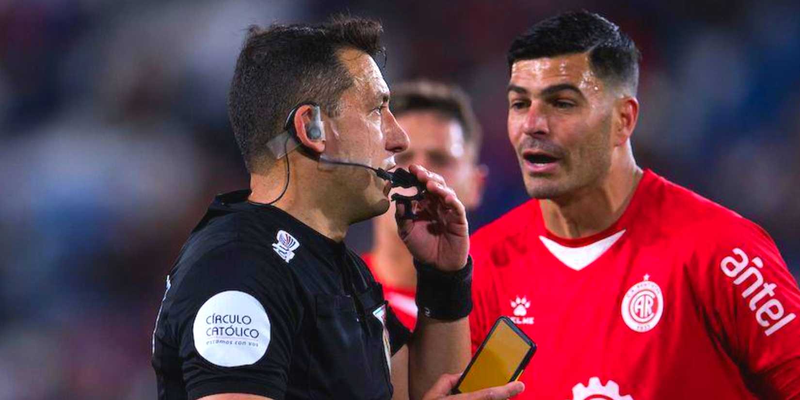 Referee Eduardo Varela uses a digital yellow card during Nacional vs Rentistas